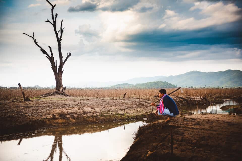 a young man overlooks a stream in a drought-stricken landscape